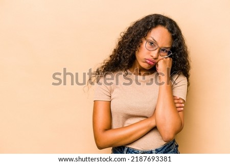 Young hispanic woman isolated on beige background who feels sad and pensive, looking at copy space.