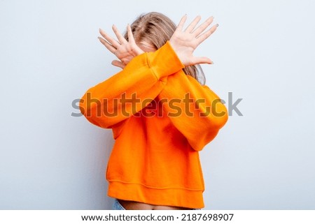 Caucasian teen girl isolated on blue background keeping two arms crossed, denial concept.