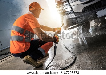 Caucasian Professional Truck Driver Pressure Washing a Vehicle. Powerful Commercial Truck Washer. Royalty-Free Stock Photo #2187705373