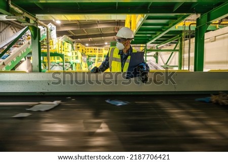 Recycling Plant Solid Waste Management Engineer Checking on Running Trash Material Conveyor. Making Documentation. Royalty-Free Stock Photo #2187706421