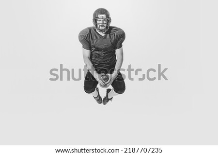 Funny moments. One american football player wearing retro stlye sports uniform in action and motion isolated on white background. Concept of sport, achievements, retro style. Monochrome