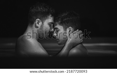 Gay couple relaxing in swimming pool. LGBT. Two young men kissing and hugging. Black and white portrait. Young men romantic family in love. Happiness concept Royalty-Free Stock Photo #2187720093