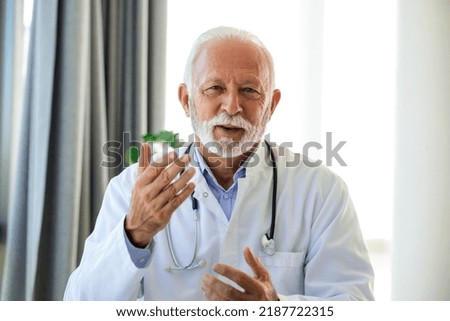 Doctor online. Senior medic talking to client on laptop computer from his office. Mature male therapist explaining medical treatment to patient through a video call with laptop in the consultation.