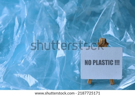 Plastic bag with text on board "no plastic" on blue background. Plastic free concept.