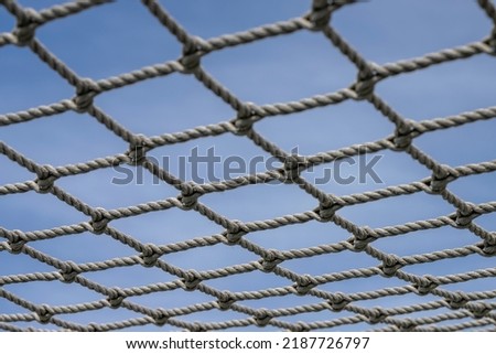 Knotted net against a blue afternoon sky in summer
