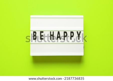 Lightbox with word be happy on green background, top view. Space for text