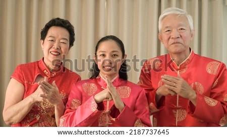 Asian family gathering Chinese New Year celebration in red traditional costume greeting red envelop Royalty-Free Stock Photo #2187737645