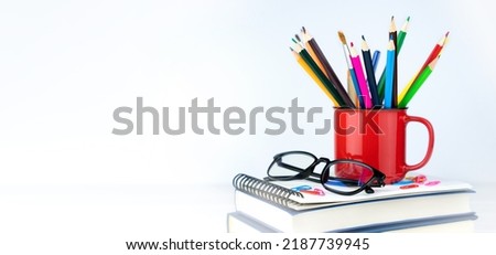 School supplies in a red mug and glasses on the books. Back to school. Banner. Mockup. Copy space. Selective focus.