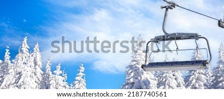 Ski resort with empty chair lift, blue sky and white snowy pine trees at winter sunny day Royalty-Free Stock Photo #2187740561