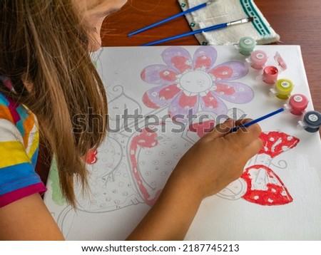Close-up of a girl's hand painting with paints on a white canvas of paper.