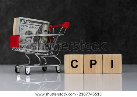 Roll of dollars in shopping cart and wooden blocks with the word cpi on dark grey background. Buy or Sell. Business and CPI, consumer price index concept Royalty-Free Stock Photo #2187745513