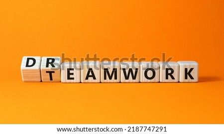 Teamwork and dream work symbol. Turned wooden cubes and changed the word 'dreamwork' to 'teamwork'. Beautiful orange background. Business, teamwork and dream work concept, copy space.