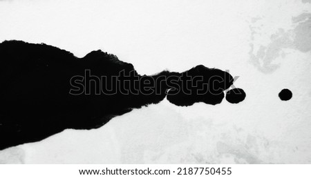 Black ink spatter on white paper. Dye drop texture. Grunge overlay. Liquid spill blob spreading on uneven abstract copy space background. Royalty-Free Stock Photo #2187750455
