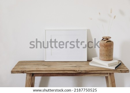 Summer, fall still life photo. Vase with dry lagurus, bunny tail grass in ceramic vase. Old wooden bench. Blank horizontal white picture frame mockup. White wall background. Empty copy space. Interior