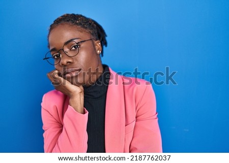 Beautiful black woman standing over blue background thinking looking tired and bored with depression problems with crossed arms. 