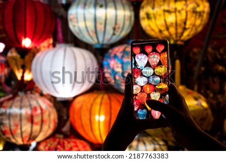 Selective focus. Tourist taking a picture of the lit lamps in Hoi An, Vietnam. Beautiful postcard of Hoi An City, Vietnam. Lit lights of Hoi An