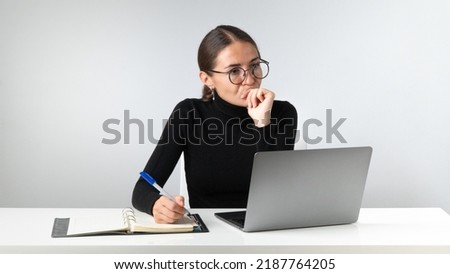 Pensive serious woman at work at a laptop in the workplace. High quality photo