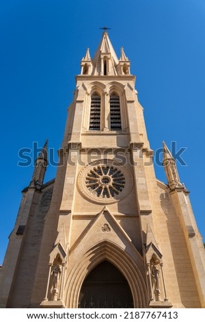 Low angle view of the facade and bell tower of ancient St Anne or St Ann catholic church, a tourism landmark of Montpellier, France, on a blue sky summer afternoon