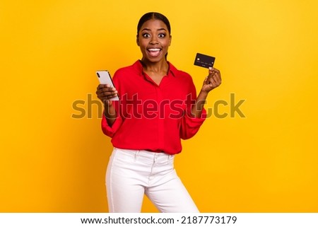Photo of young excited girl shopping order bank card benefit cashback profit use mobile isolated over yellow color background