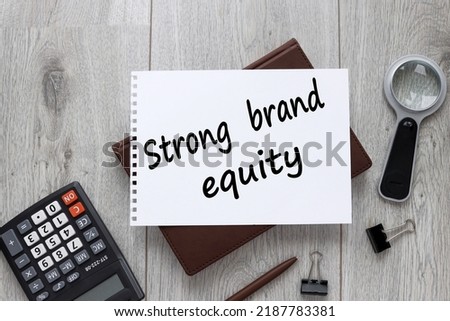 STRONG BRAND EQUITY notepad on wooden background with text and calculator