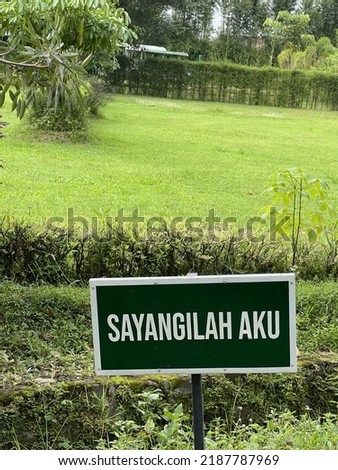 a sign of sayangilah aku or loves me in indonesian language on the grass