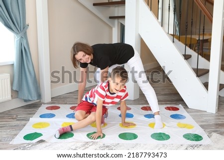 Twister game. Happy family having fun together, playing twister game at home. Mother and child, kid, boy plays in twister. Active rest, recreation, indoor game. Child with parent plays twister game Royalty-Free Stock Photo #2187793473