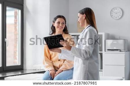 medicine, healthcare and people concept - female doctor with tablet pc computer talking to smiling woman patient at hospital Royalty-Free Stock Photo #2187807981