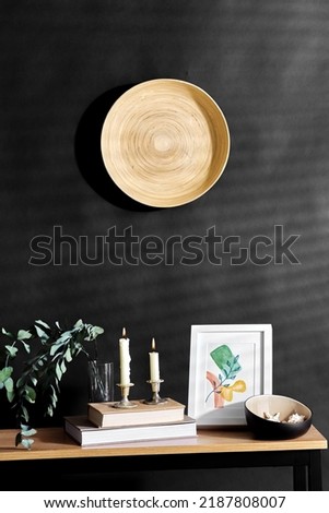 interior and home decor concept - bench with burning candles, picture in frame, books, seashells and eucalyptus branches over black background