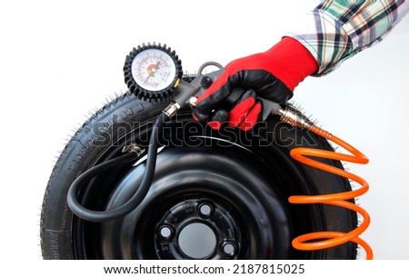 Mechanic inflates tires and checks air pressure with a pressure gauge, close-up on an isolated white background Royalty-Free Stock Photo #2187815025