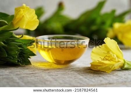 Evening primrose oil in a bowl with fresh blooming Oenothera biennis plant on a table Royalty-Free Stock Photo #2187824561