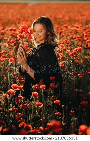 a girl in a black dress on a poppy field at sunset.