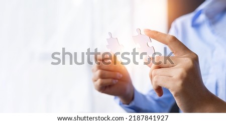 Cropped shot of Businesswoman hand connecting jigsaw puzzle with sunlight effect, Business solutions, success, and Assembling jigsaw pieces, strategy ideas. Royalty-Free Stock Photo #2187841927