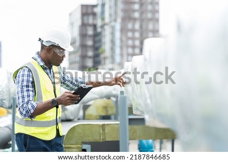 Male engineer or male technician work with digital tablet at construction site area. African American male engineer worker check or maintenance pipe system for ventilation and air conditioning Royalty-Free Stock Photo #2187846685