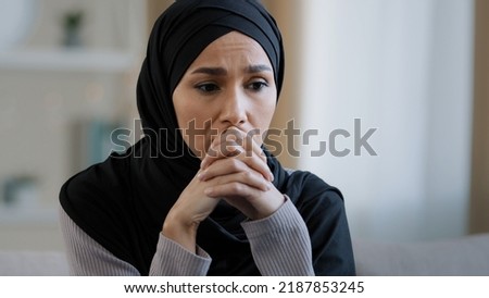 Upset sad girl in hijab sit alone get bad news feel depressed frustrated muslim woman suffering from illness worried about unresolved problems feeling sorrow grief hard divorce need psychological Royalty-Free Stock Photo #2187853245