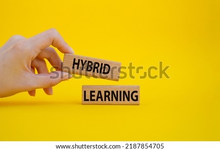 Hybrid learning symbol. Concept word Hybrid learning on wooden blocks. Beautiful yellow background. Businessman hand. Business and Hybrid learning concept. Copy space