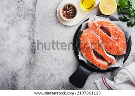 Salmon. Raw salmon steak. Fresh raw salmon fish with cooking ingredients, herbs and lemon prepared for grilled baking on light grey background. Healthy food. Top view. Copy space.