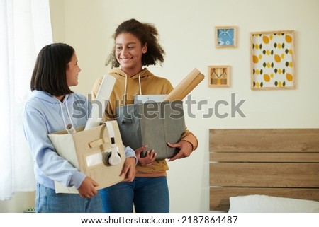 Smiling teenage roommates with boxes of belongings meeting each other for the first time Royalty-Free Stock Photo #2187864487