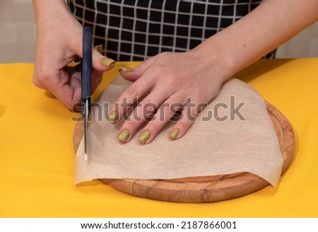 Women's hands cut off the excess part from the parchment. Close-up. Selective focus. Images for articles about confectionery.