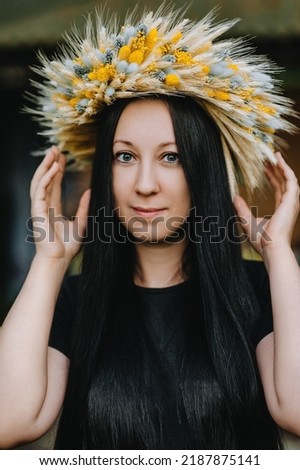 Close-up portrait of a beautiful, young blonde Ukrainian girl with a wreath of wheat and wildflowers. National tradition, ritual.
