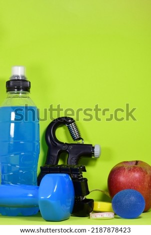 Hand grip fitness training and various accessories, dumbbells and healthy eating, on a green background.