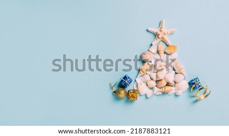 Creative Christmas tree from sea shells, small gifts blue background. Concept tropical new year