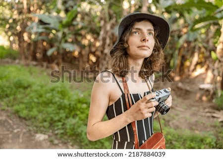 Pretty woman in black hat using photo camera in Africa national park. Travel