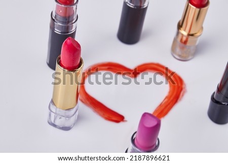 Close up set of various lipstiks on white background. Drawn red heart. Love or valentines day concept.