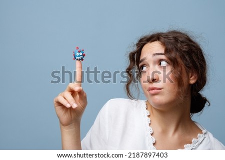 Young woman holds the puppet of a COVID-19 virus on her finger without any fear; concept of the new normal and the power of science and knowledge