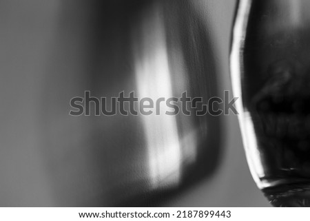 Glass bottle cast beautiful shadow and caustic effect as light passes through a glass. Black and white photo. Abstract background Royalty-Free Stock Photo #2187899443
