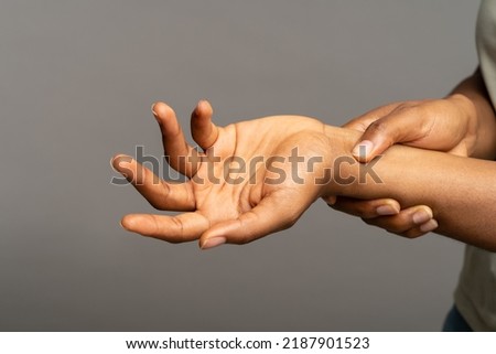 Close up of african woman arms holding painful wrist after work on laptop computer, suffering from weakness and tingling, carpal tunnel syndrome, arthritis, neurological disease. Numbness of hand Royalty-Free Stock Photo #2187901523