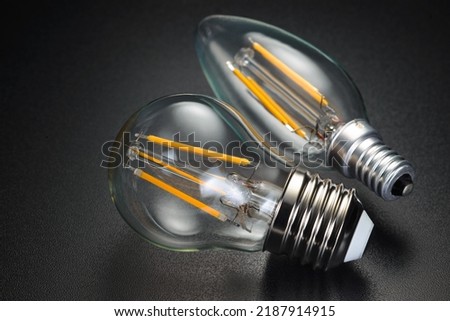 Old-fashion transparent LED filament bulbs on black background. Royalty-Free Stock Photo #2187914915