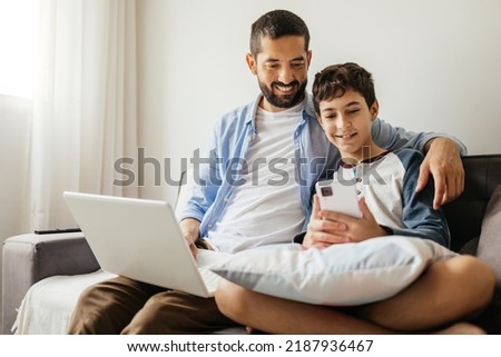 Father and his teenage son spending time together at home. Royalty-Free Stock Photo #2187936467