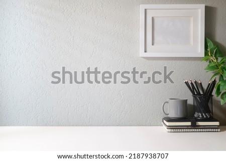 Blank picture frame, coffee cup, notebook and house plant. Home office desk, Copy space for your text.