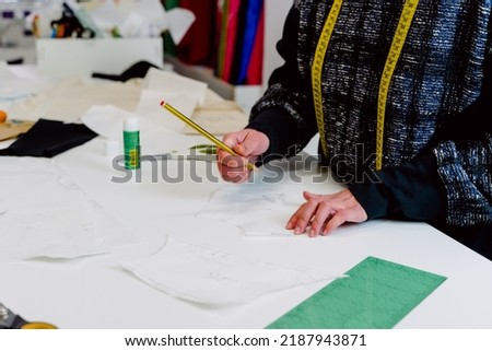 woman designing the clothes she creates in her workshop with pencil and paper.